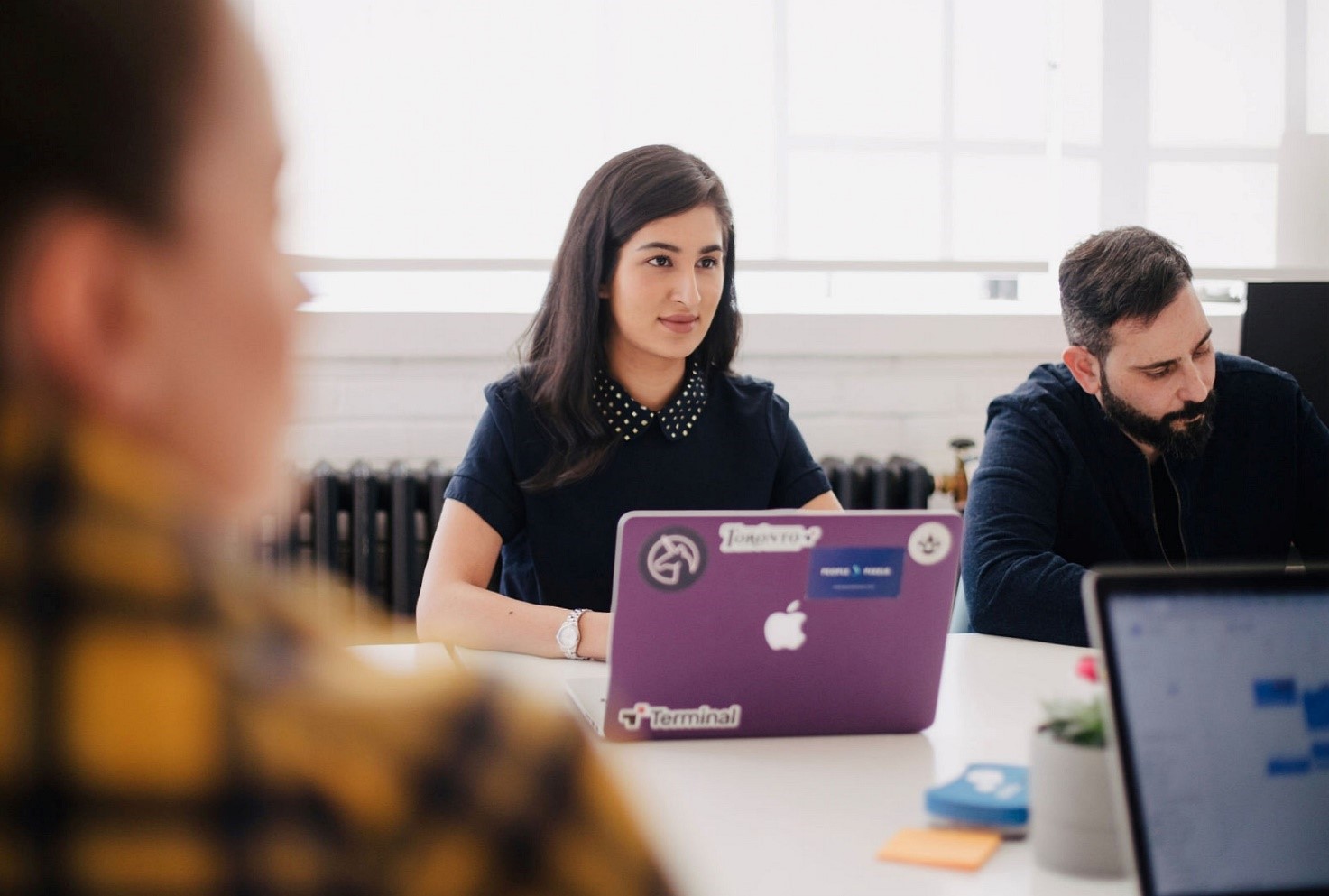 ragazza millennial con macbook viola in una riunione di lavoro con i colleghi