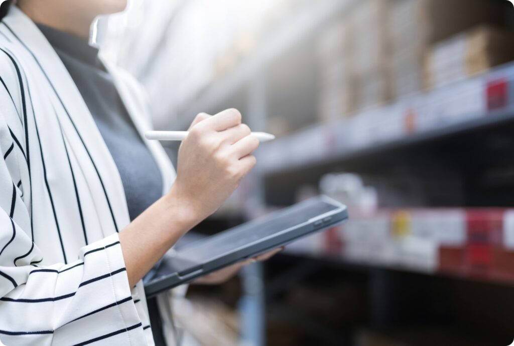 donna con tablet e penna touch fa l'inventario in un magazzino